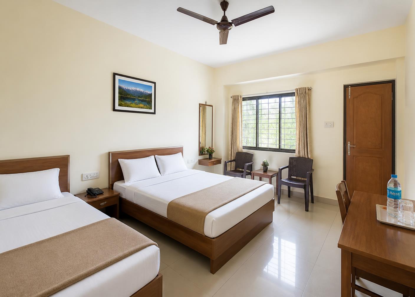 Neat budget non-AC room with two beds, ceiling fan and clean tiled floor
